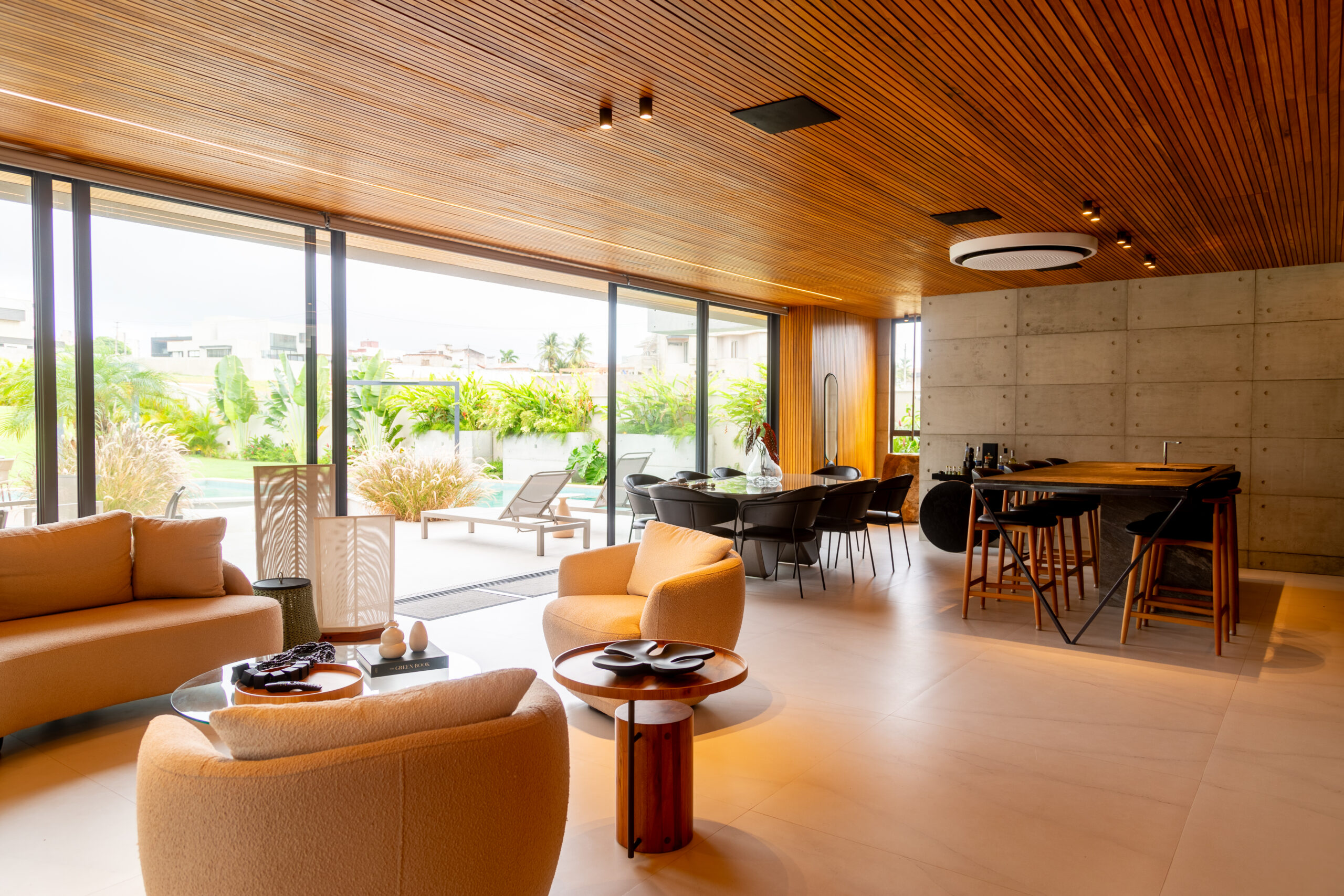 Sala moderna integrada com iluminação natural através de grandes janelas de vidro.